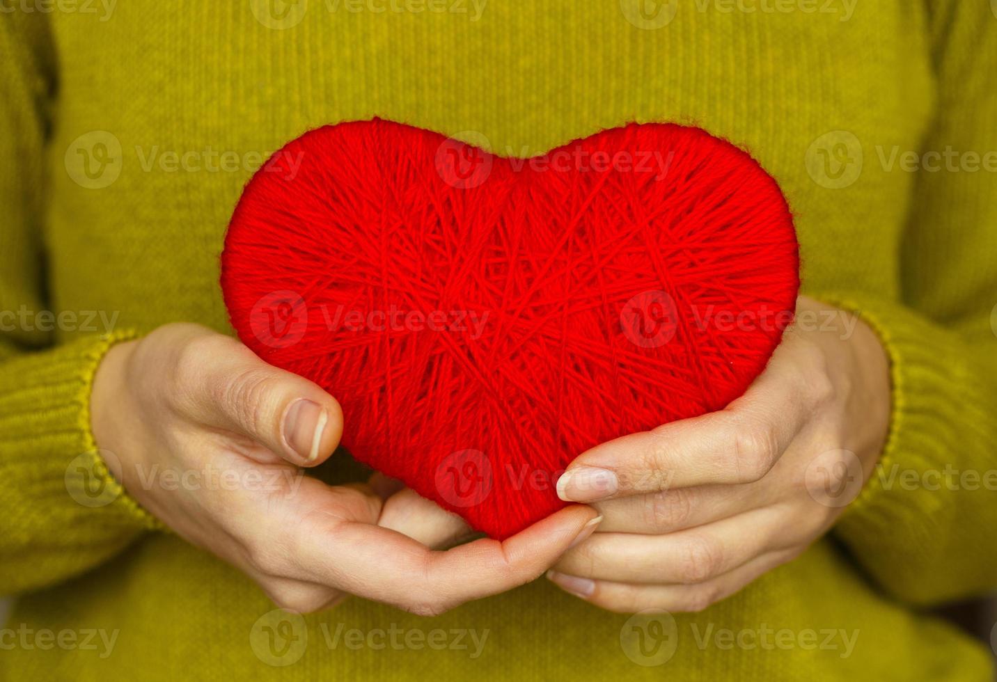 Closeup on red heart made from wool in hand of woman photo