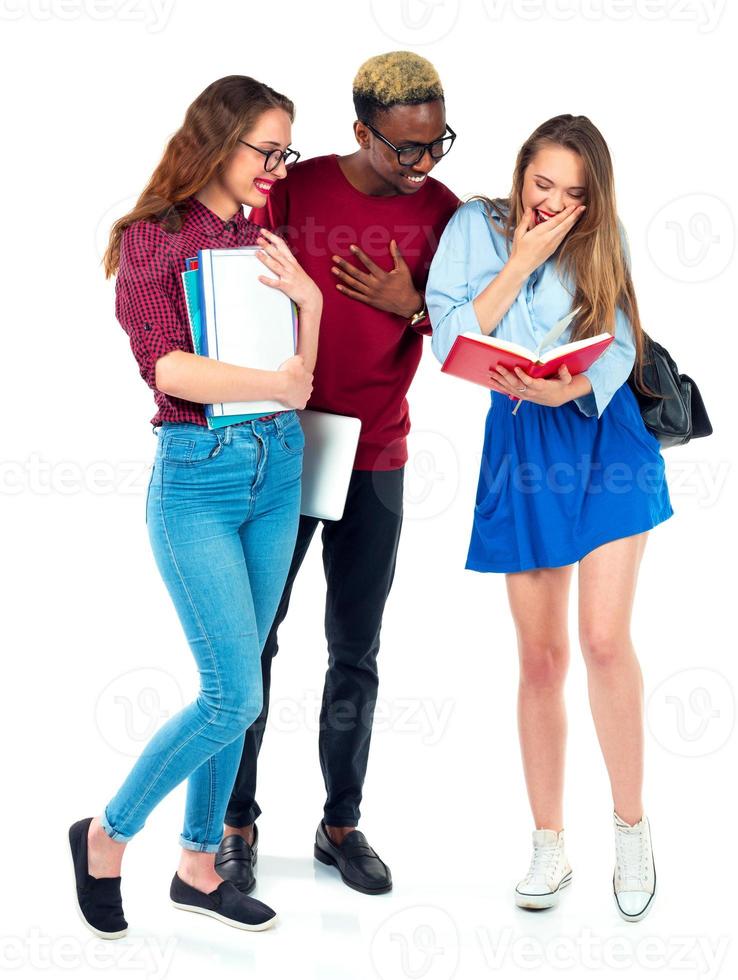 contento estudiantes en pie y sonriente con libros, ordenador portátil y pantalones aislado en blanco foto