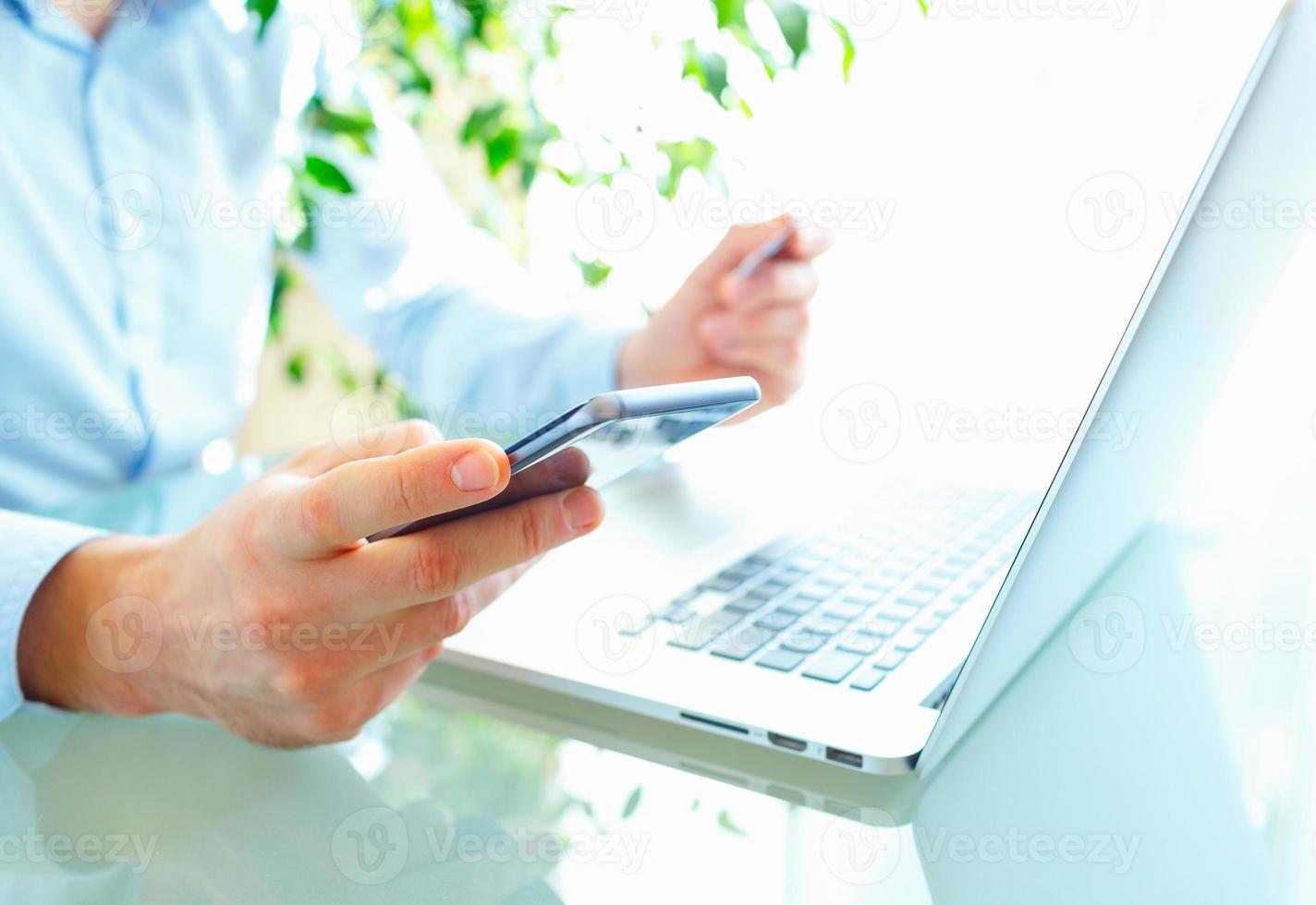 Men office worker typing on the keyboard and using smartphone photo