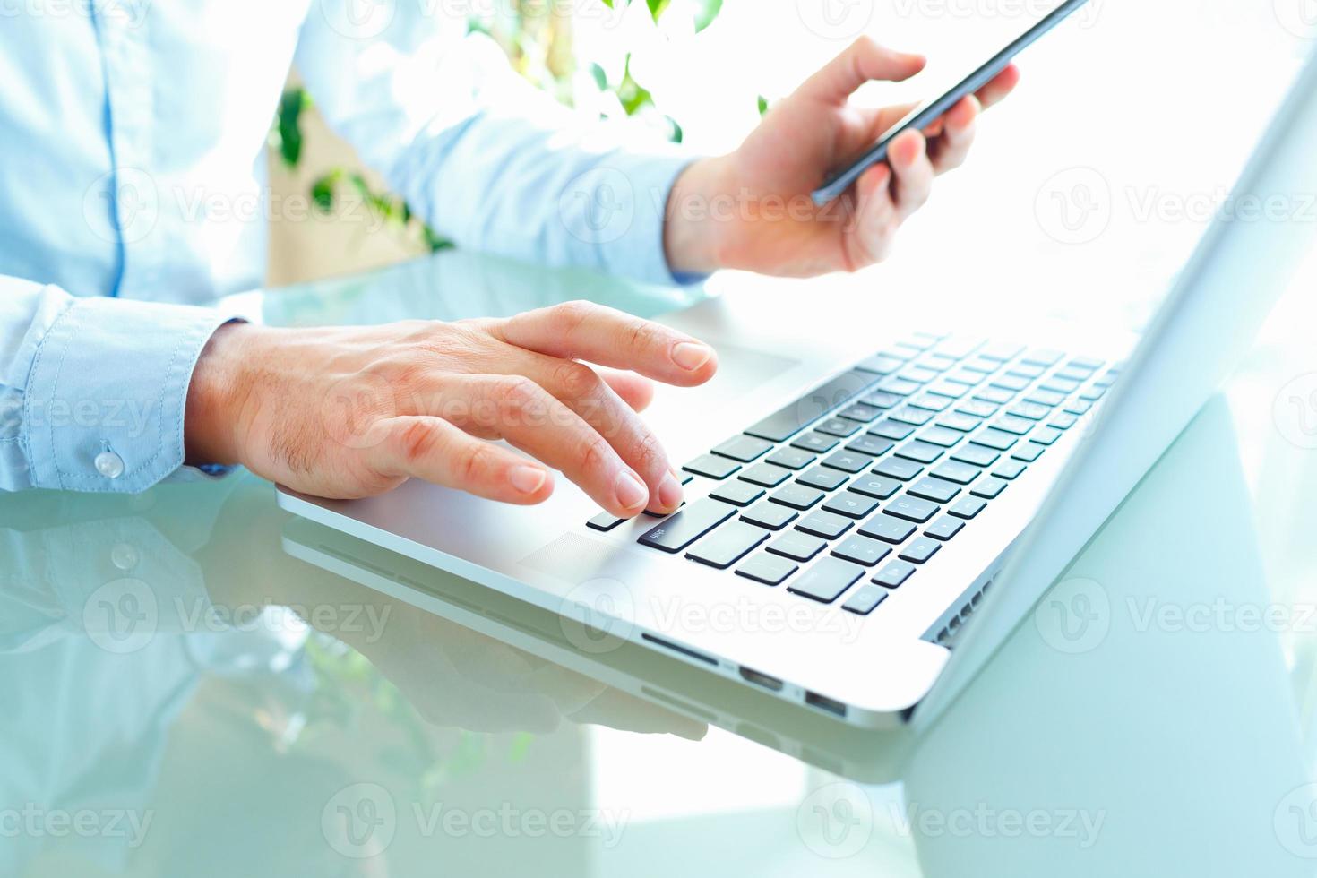 Men office worker typing on the keyboard and using smartphone photo