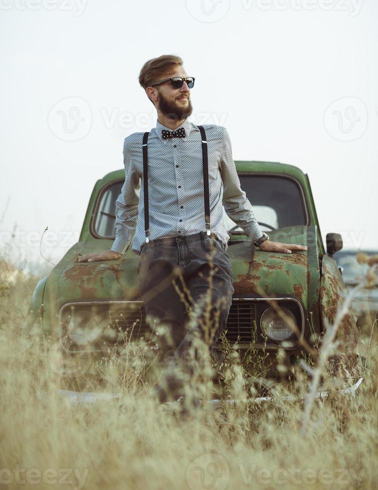 Young handsome stylish man, wearing shirt and bow-tie with old cars photo