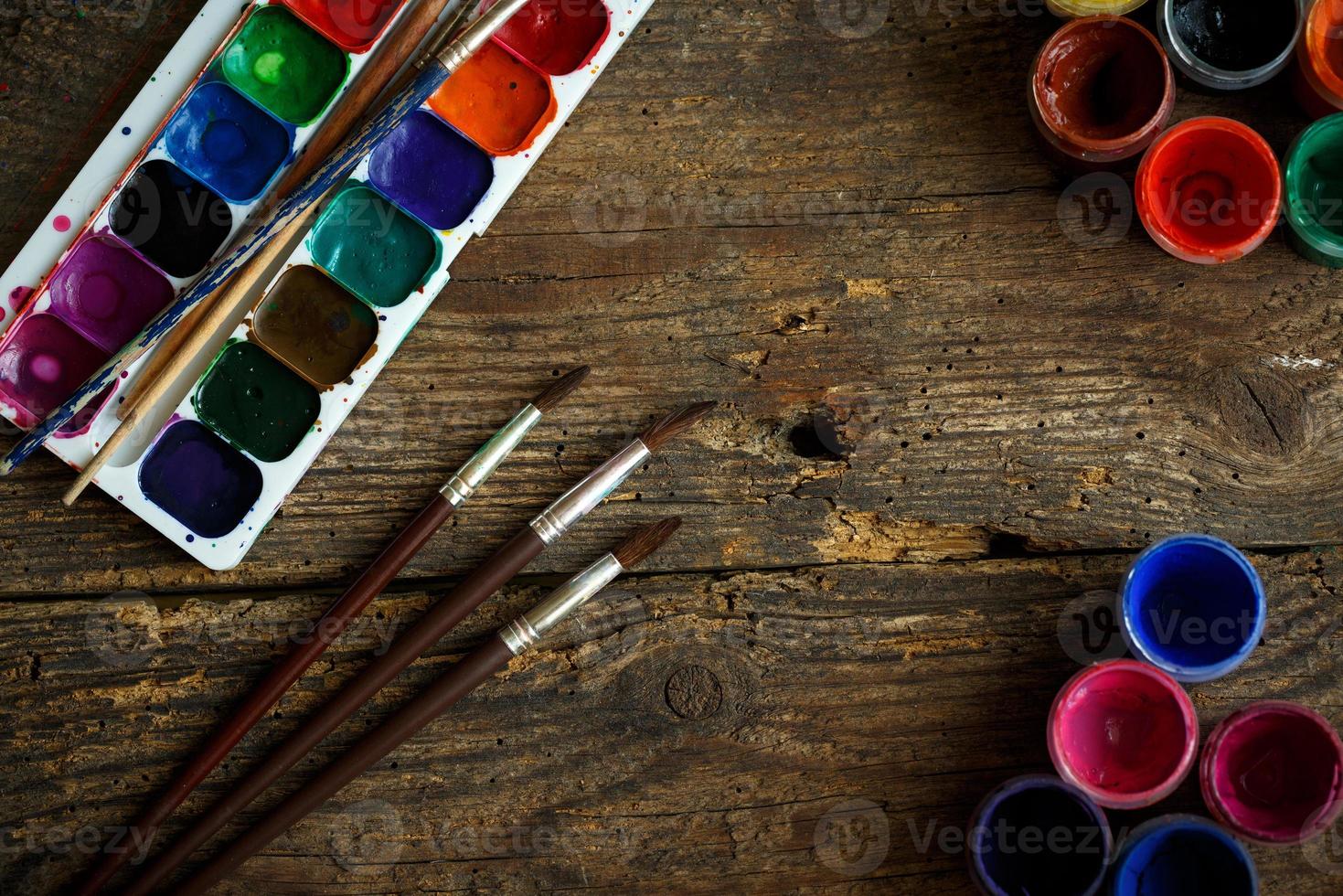 Watercolors and paint brush on wooden background photo