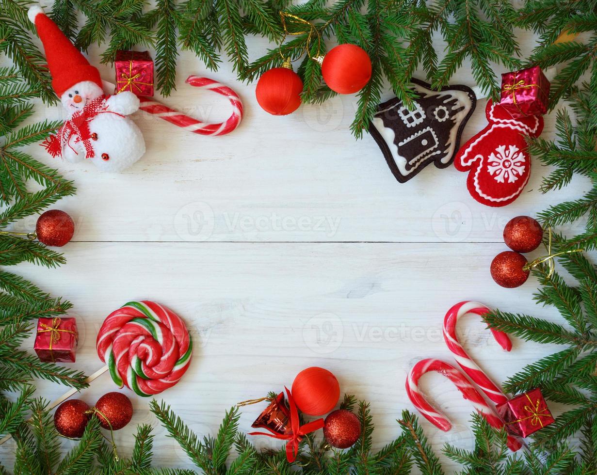 Christmas border with fir tree branches, christmas decorations and candy cane on white wooden boards photo