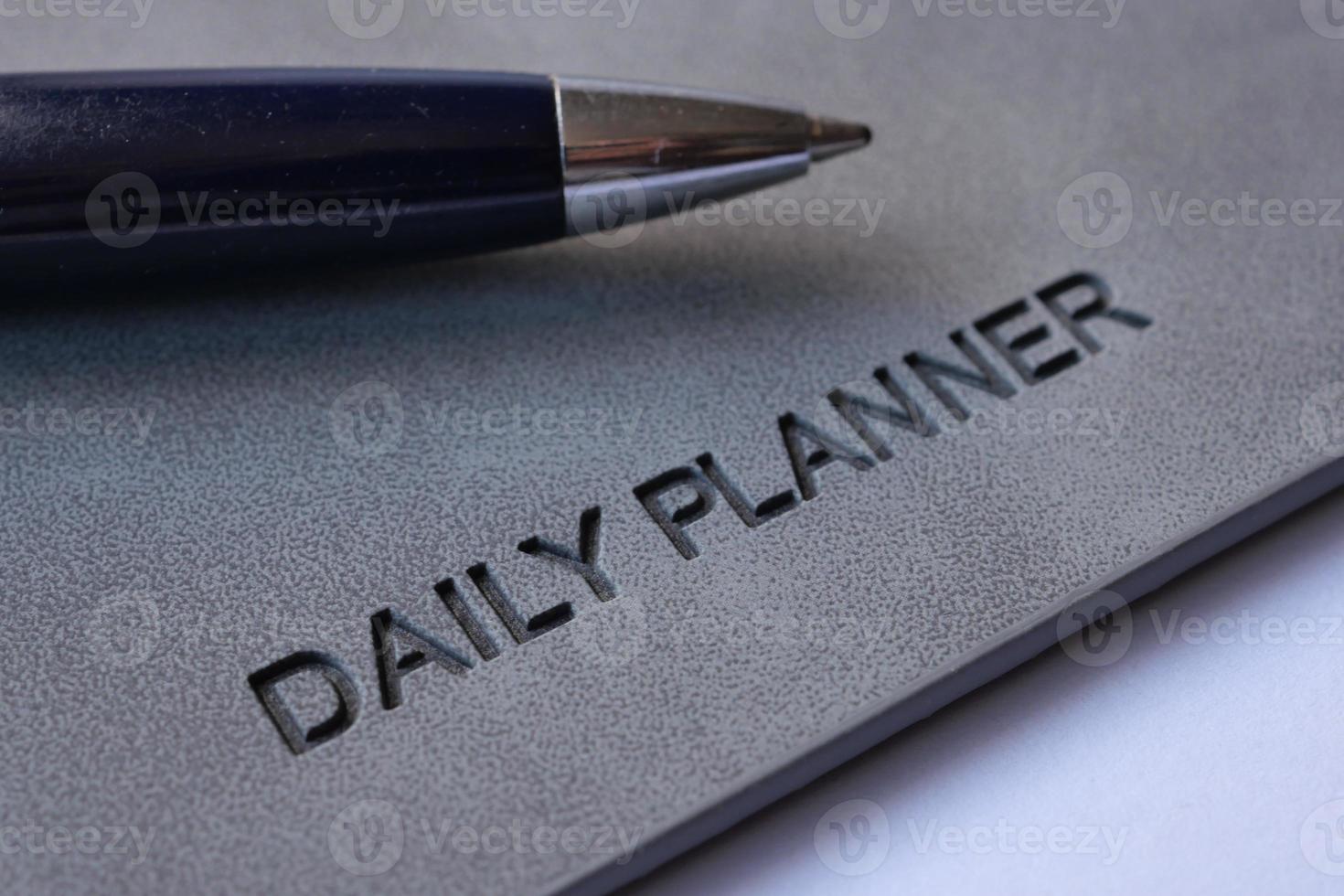 daily planner and a pen on table photo