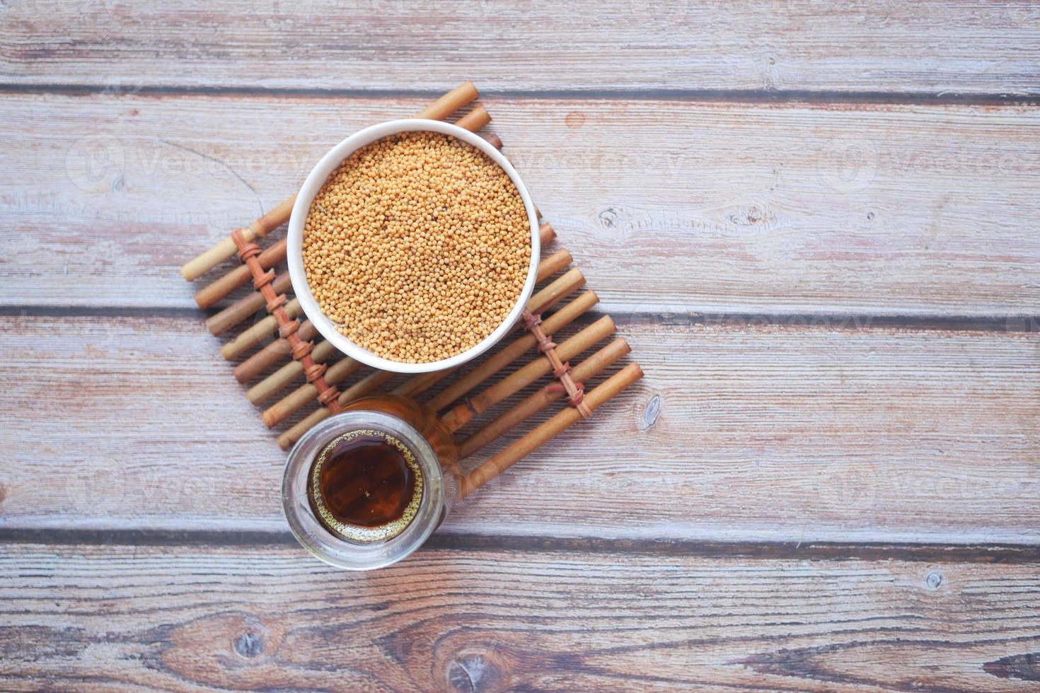 Mustard oil and raw seed in jar on table photo