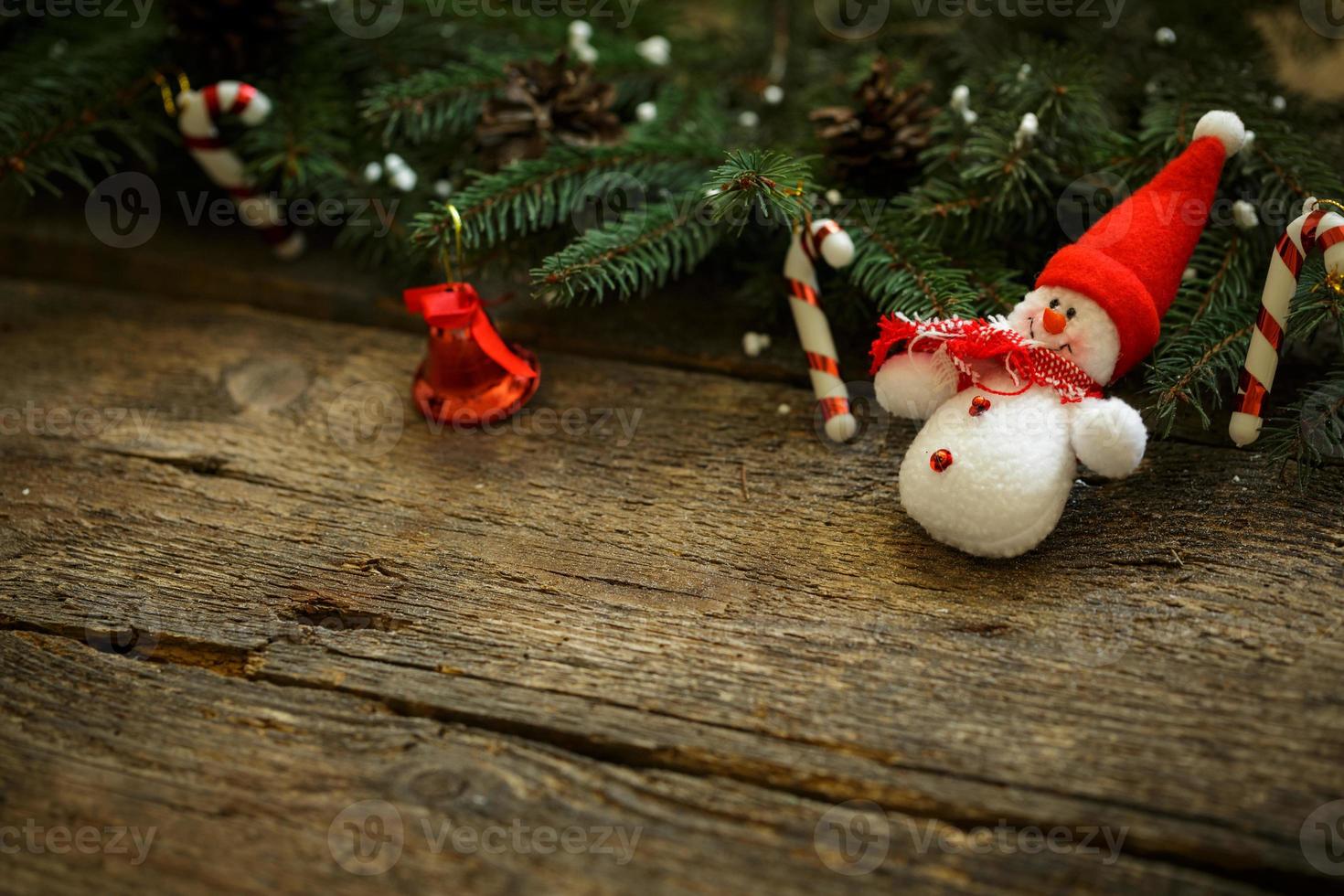 Christmas tree branches with christmas decorations and snowman on wooden texture photo