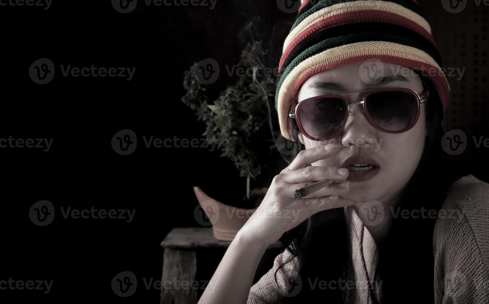 Beautiful Asia women smoking weed at cannabis tree background photo