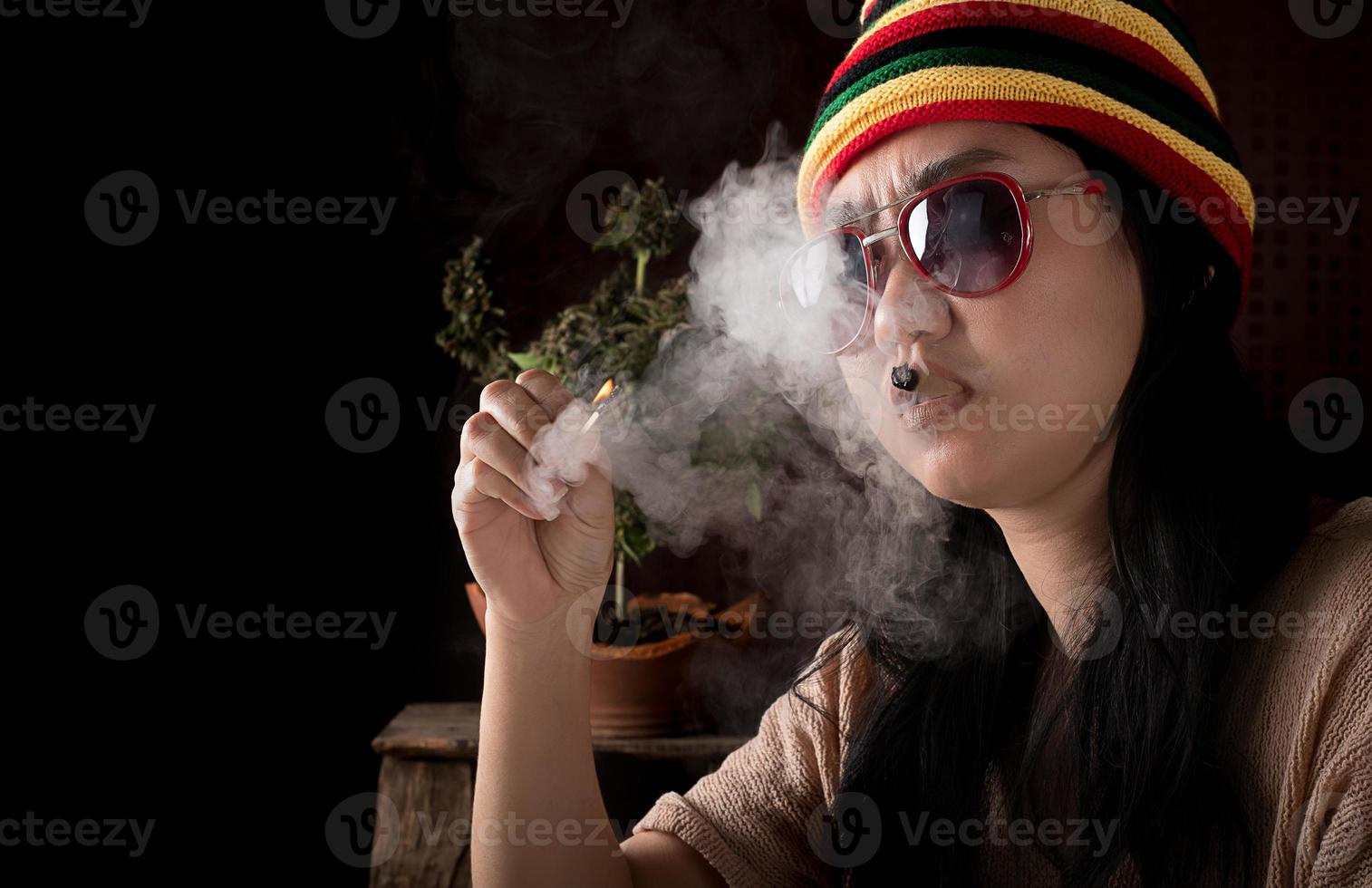 hermosa Asia mujer de fumar cigarrillos a canabis árbol antecedentes foto