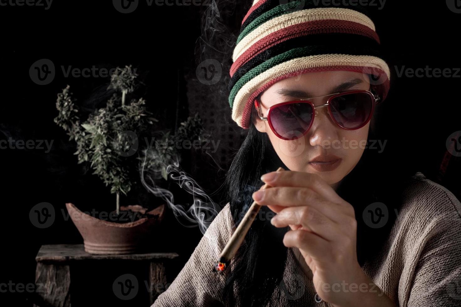 Beautiful Asia women smoking weed at cannabis tree background photo