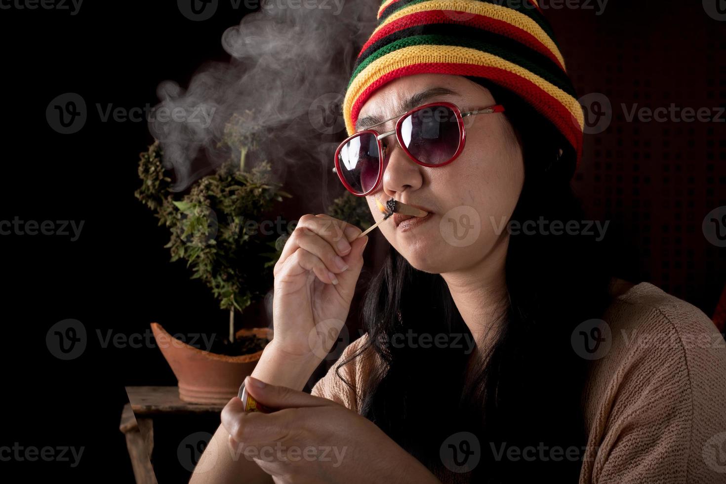 Beautiful Asia women smoking weed at cannabis tree background photo