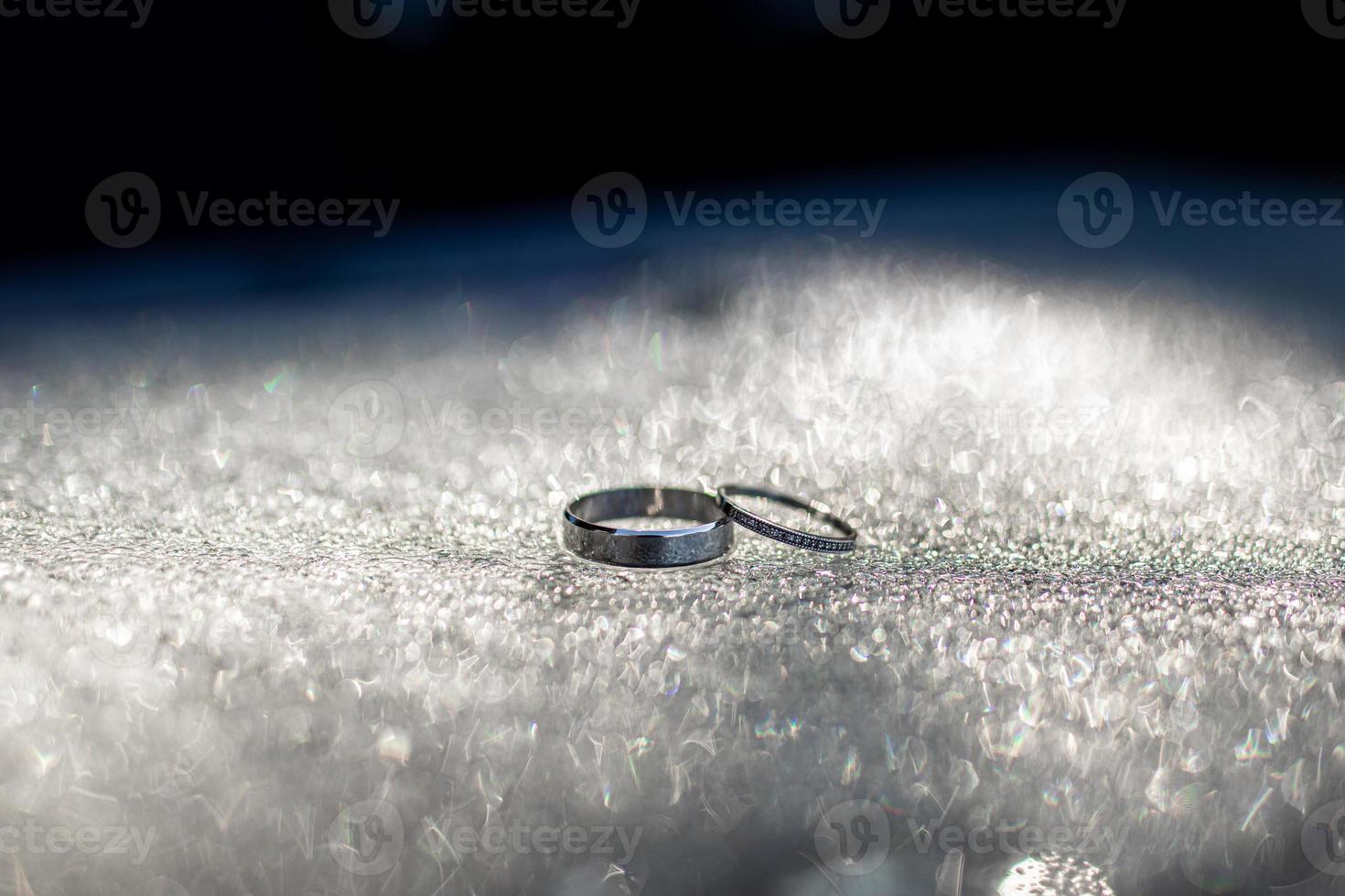 Two beautiful white gold wedding rings in drops of water. photo