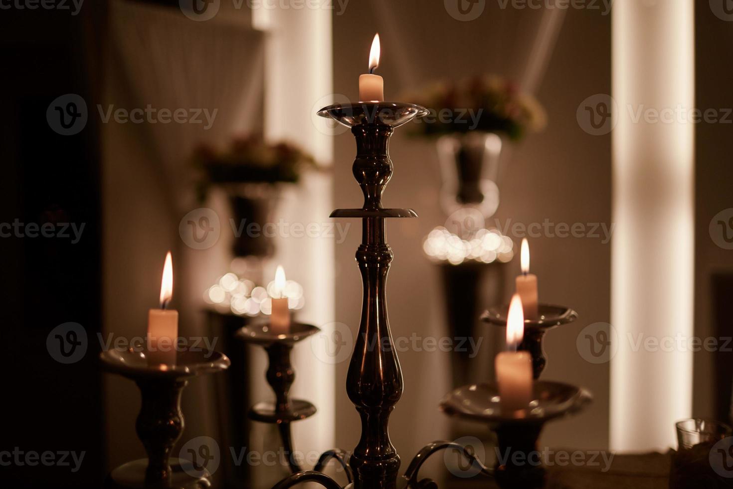 velas encendidas en candelabro de bronce contra un fondo oscuro en casa velas en el interior. estilo vintage. ambiente romántico tranquilo. imagen horizontal para el diseño. foto