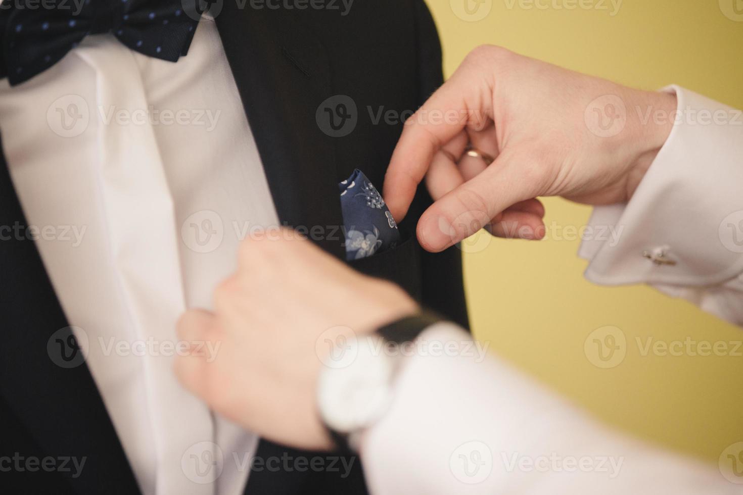 Preparations for the wedding.Groomsmen helping groom getting ready in the morning in the room. photo