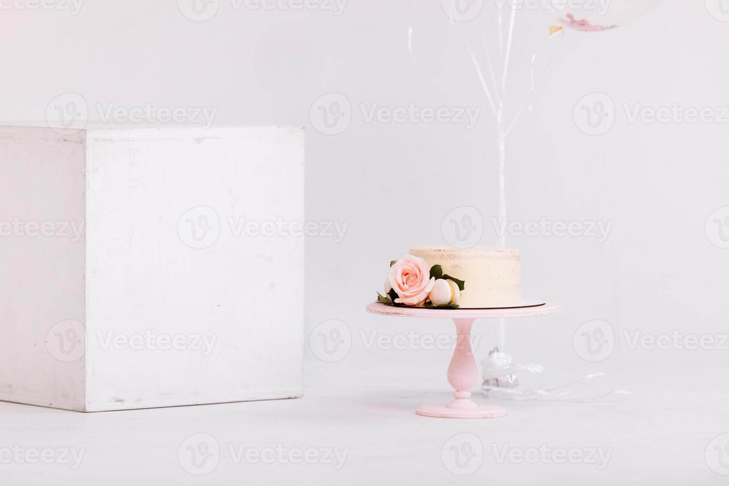 Beautiful white cream cake decorated with 2 year old candle and roses in white studio. Birthday party - Concept of a year of birth, party, celebration of life and memorable moments. photo