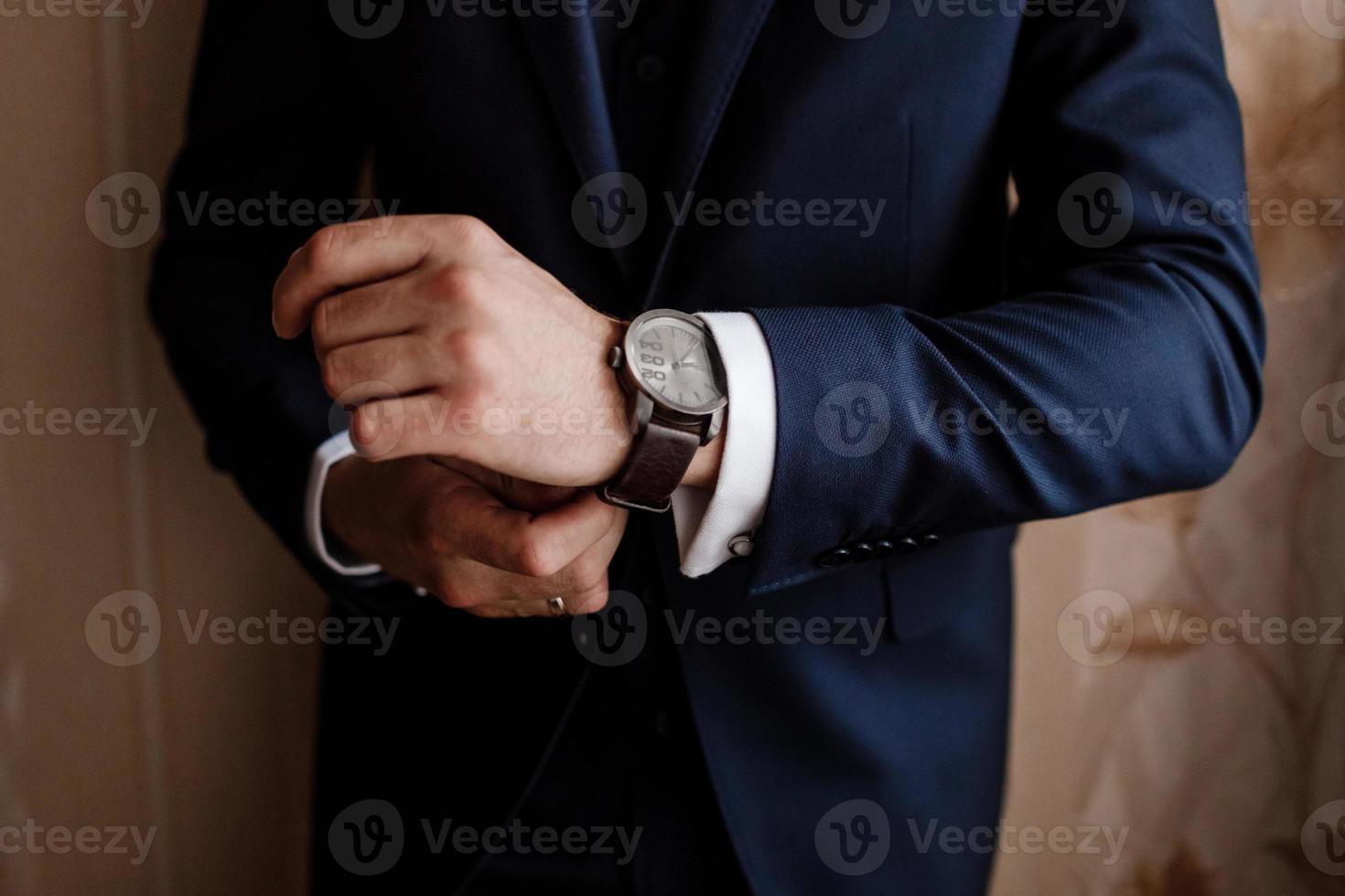 businessman checking time on his wrist watch, man putting clock on hand,groom getting ready in the morning before wedding ceremony. man puts on a watch. selective focus photo