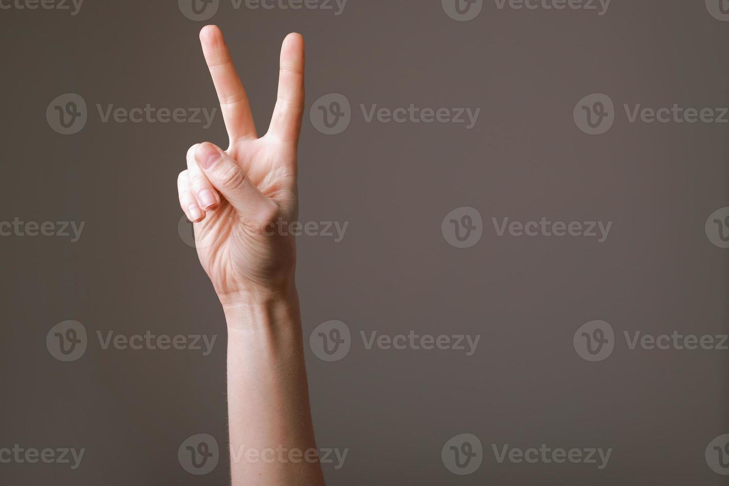 Woman hands isolated showing victory sign on grey background, gesture of victory. Policy position and belief. photo