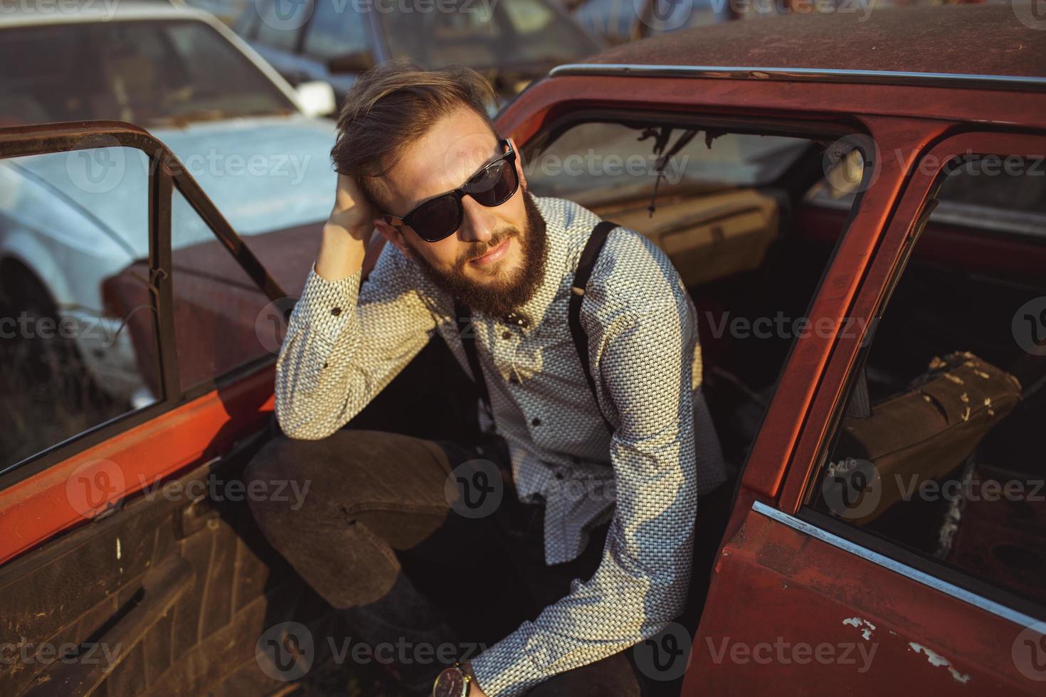 Young handsome stylish man, wearing shirt and bow-tie with old cars photo