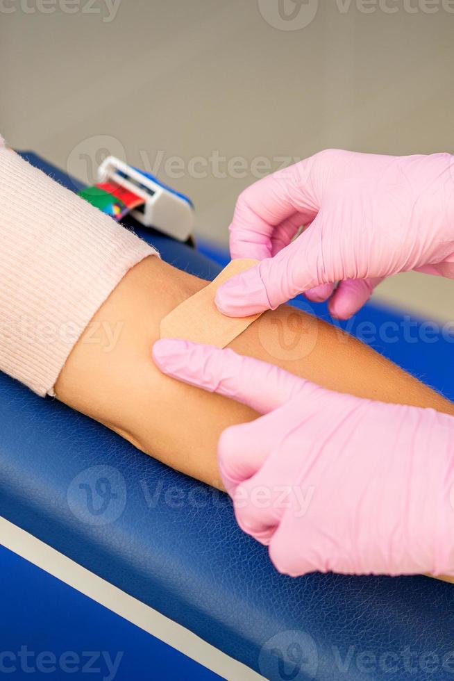 Nurse applying adhesive plaster on arm photo