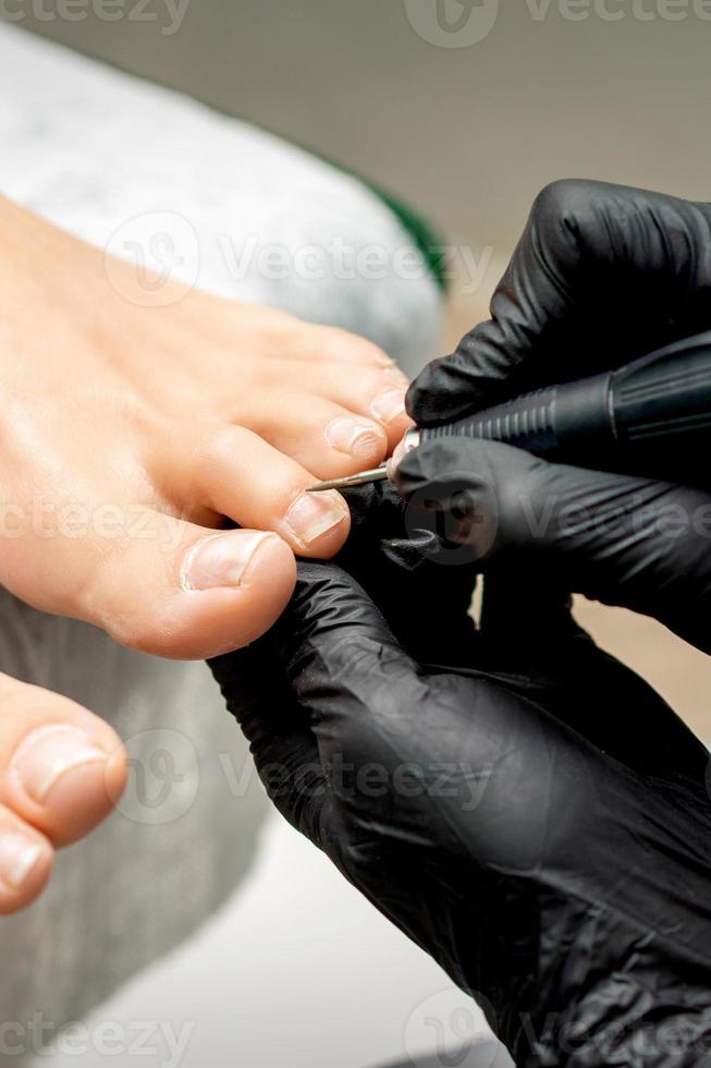 Pedicurist removes cuticle from toes photo
