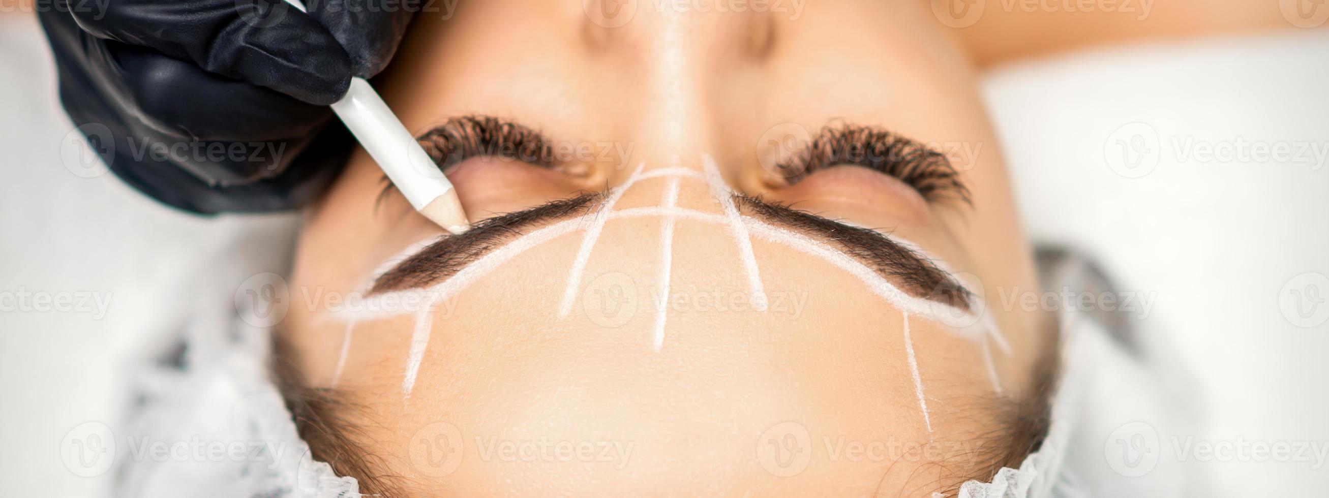 Beautician marking eyebrows with pencil photo