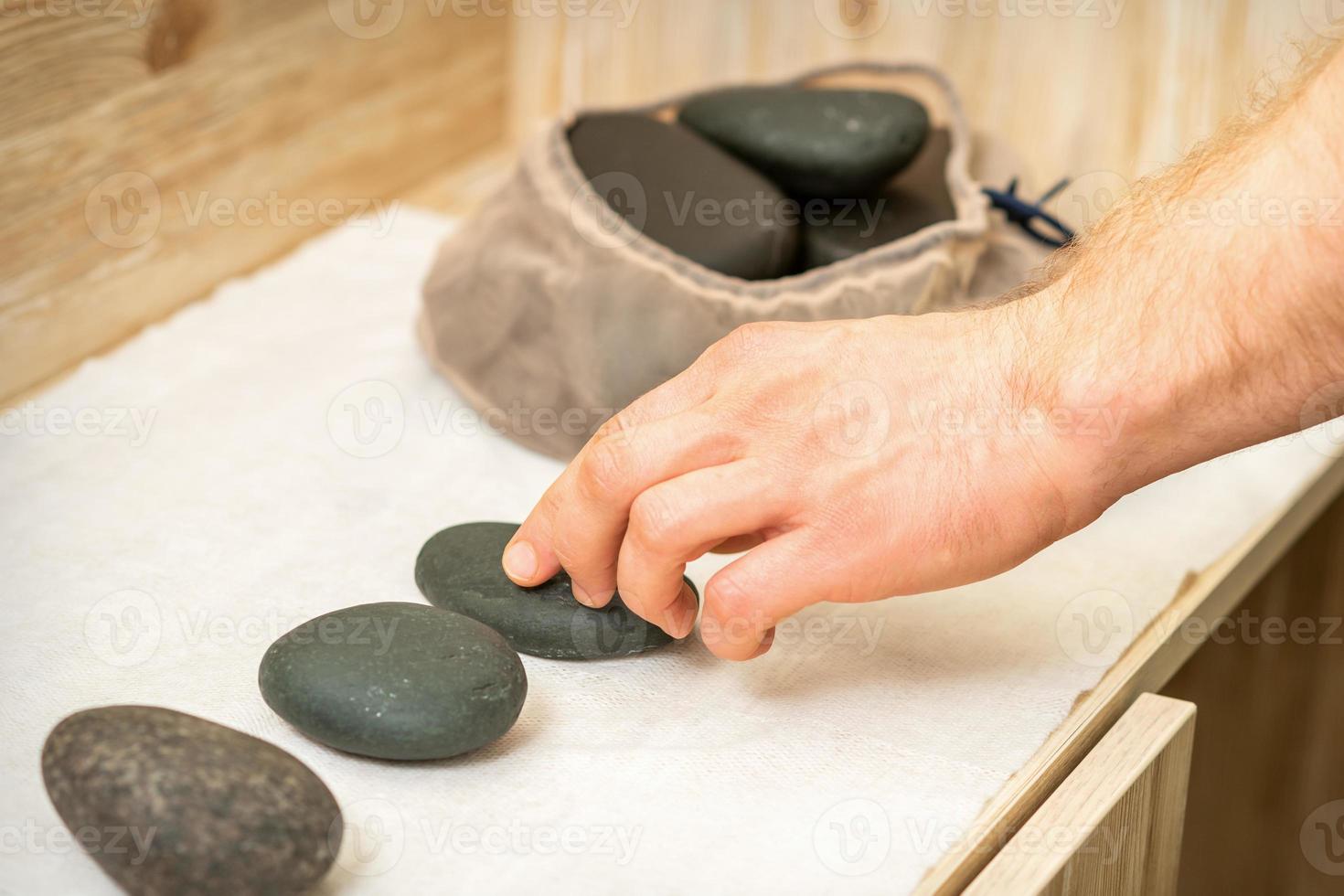 Masseur takes black massage stones photo