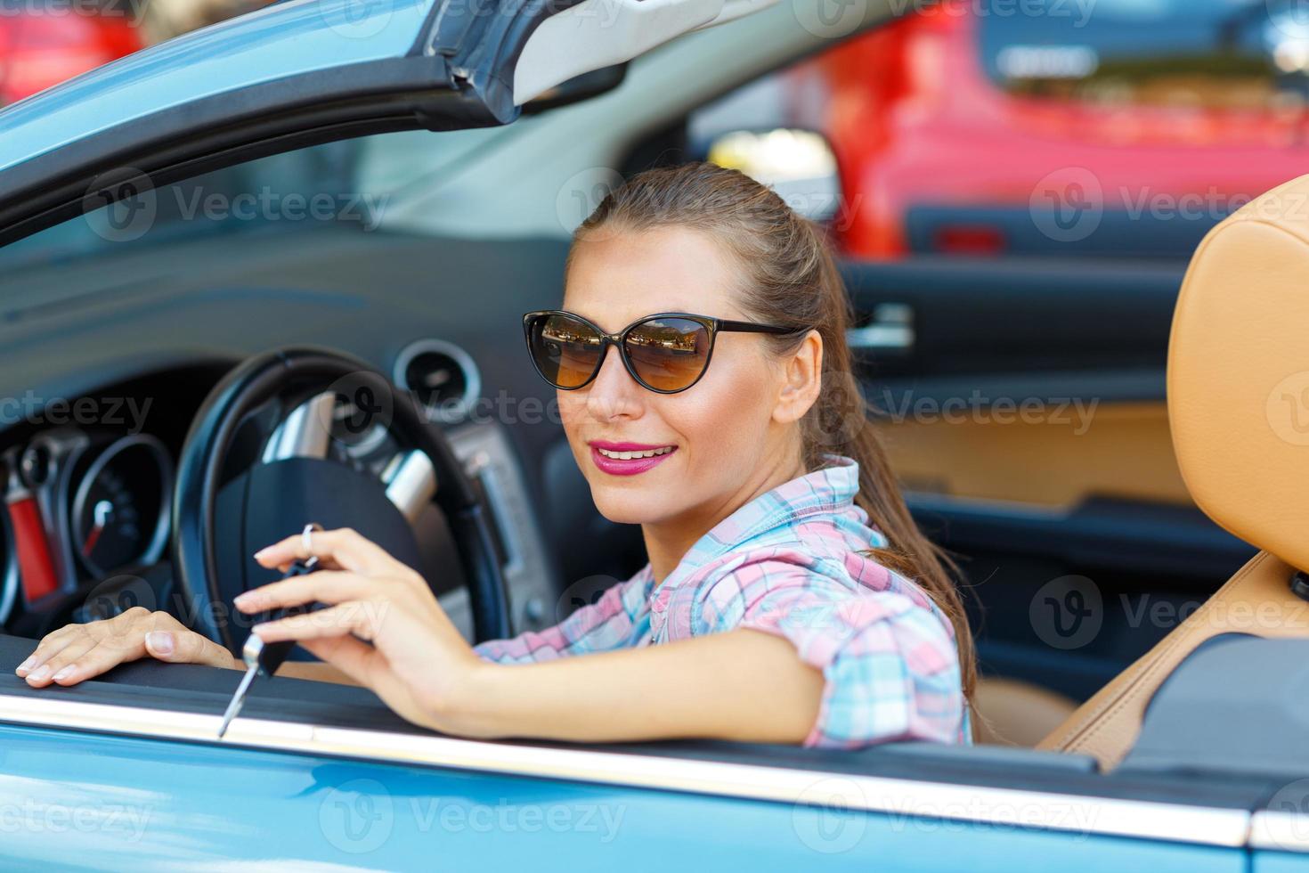 mujer en Gafas de sol sentado en un convertible coche con el llaves en mano - concepto de comprando un usado coche o un alquiler coche foto
