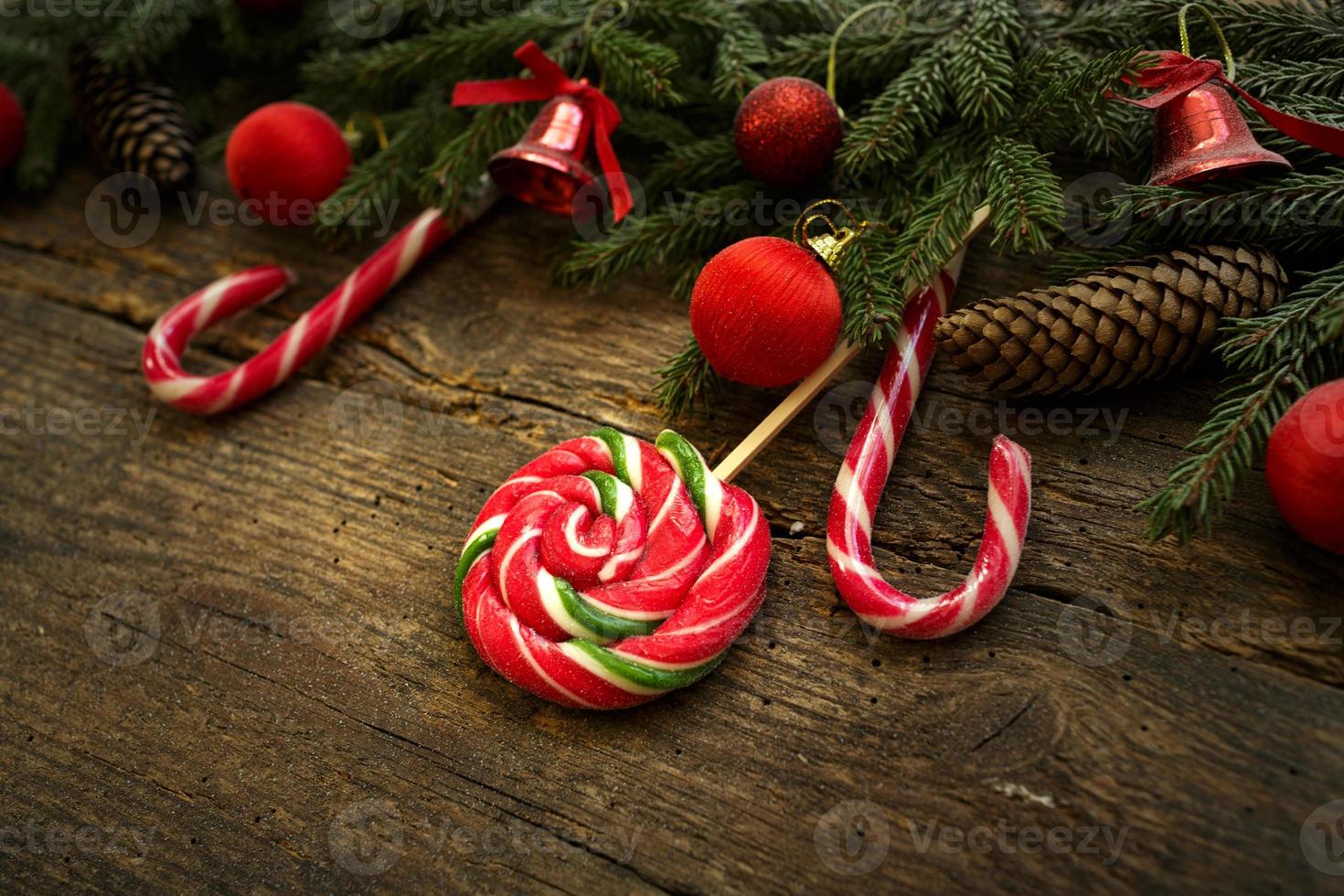 Christmas border with fir tree branches, cones, christmas decorations and candy cane on rustic wooden boards photo