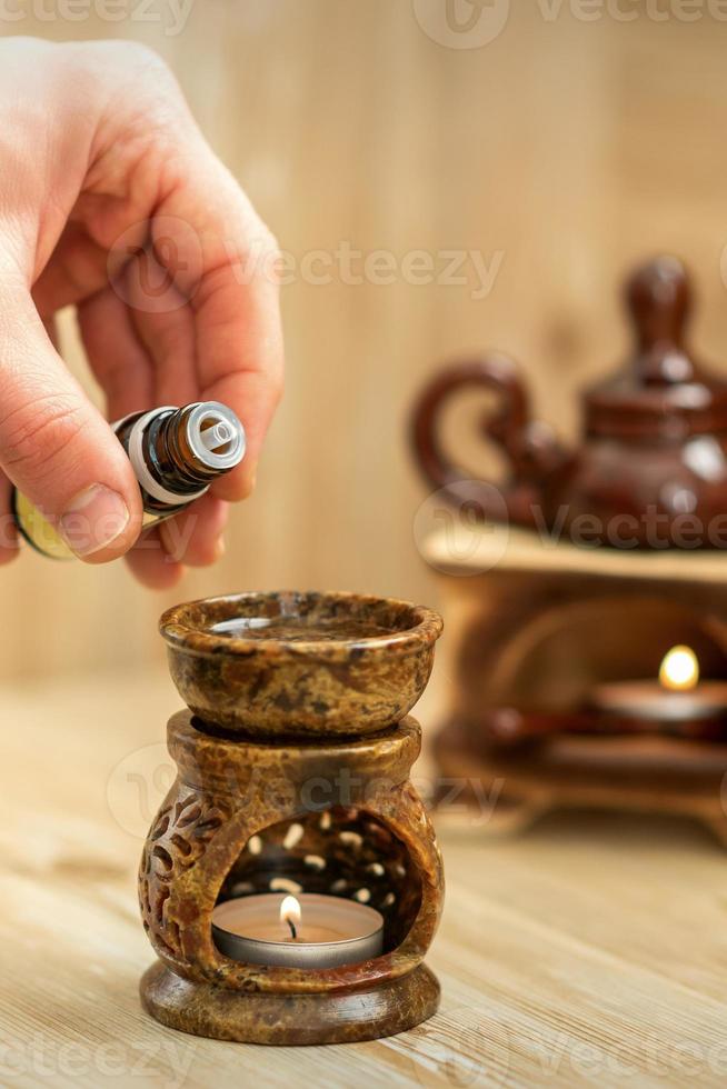 Hand pours essential oil to diffuser photo