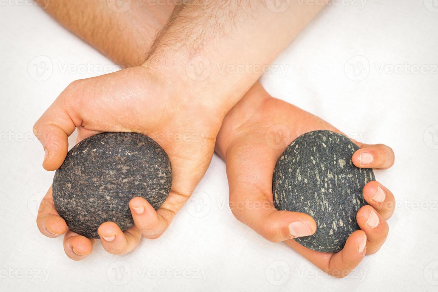 Masseur holding hot massage stones photo