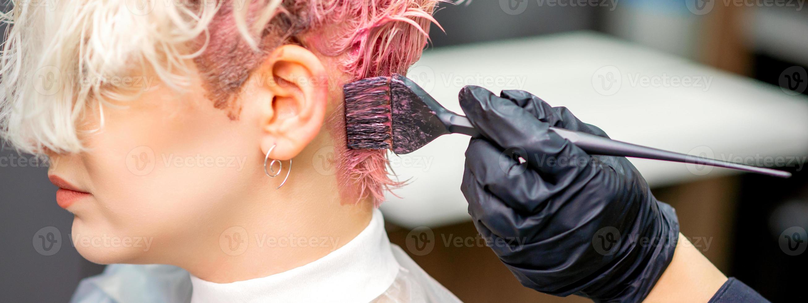 Hairdresser dyeing hair in pink color photo