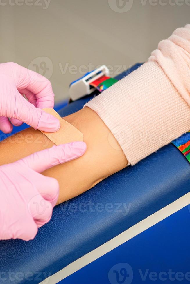 Nurse applying adhesive plaster on arm photo