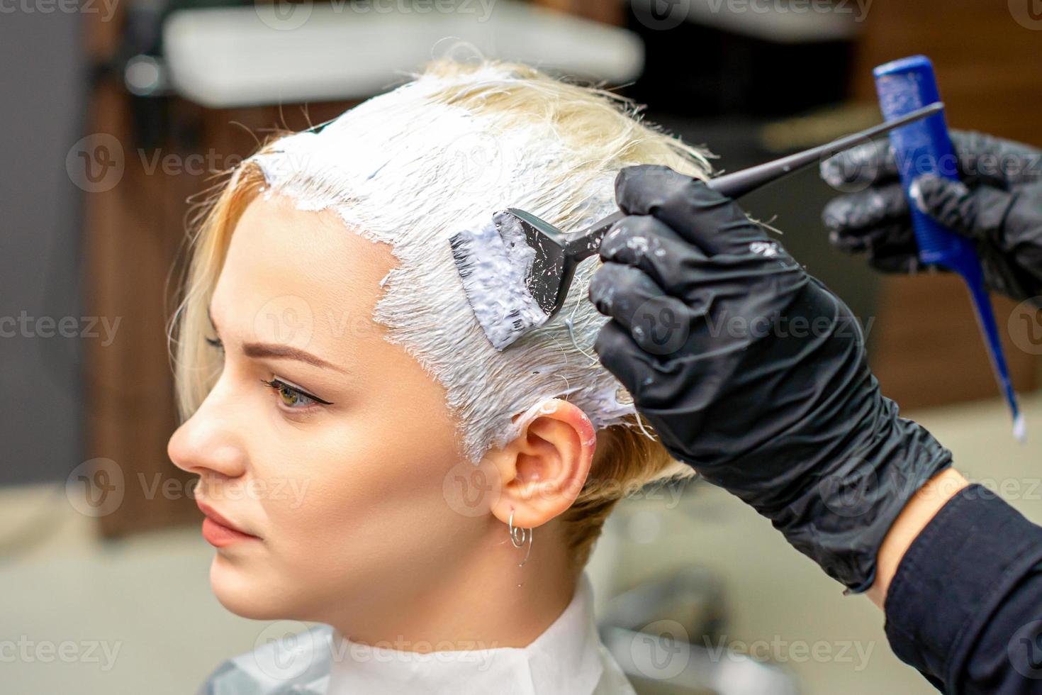 Hairdresser applying white dye to hair photo