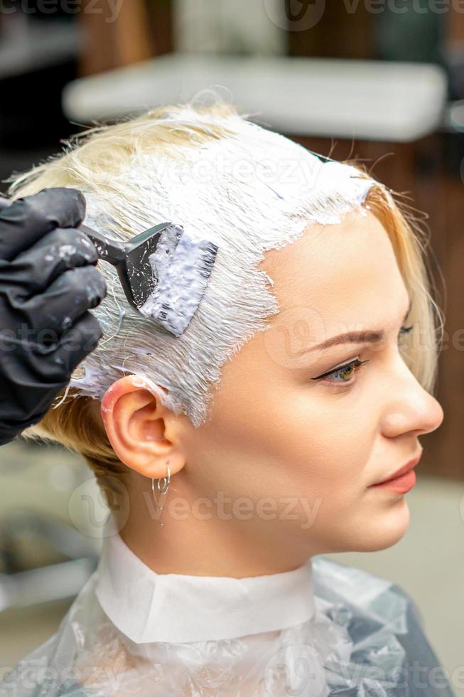 Hairdresser applying white dye to hair photo
