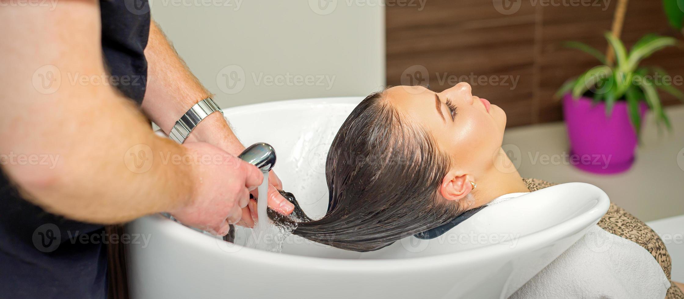 Hairdresser rinses hair of woman photo