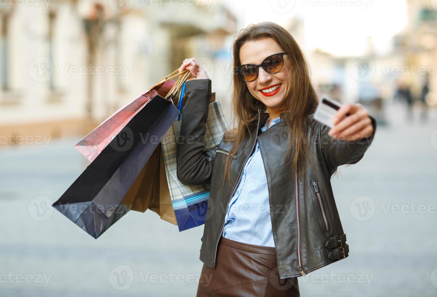 Beautiful woman with shopping bags and credit card in the hands on a street photo