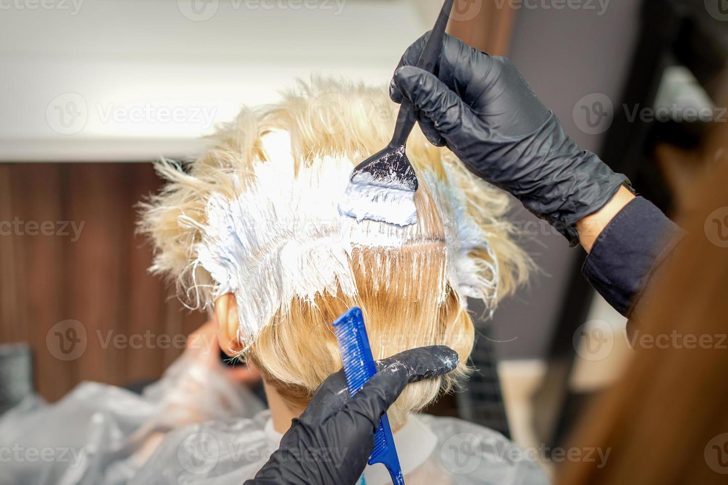 Hair stylist dyeing hair of woman photo