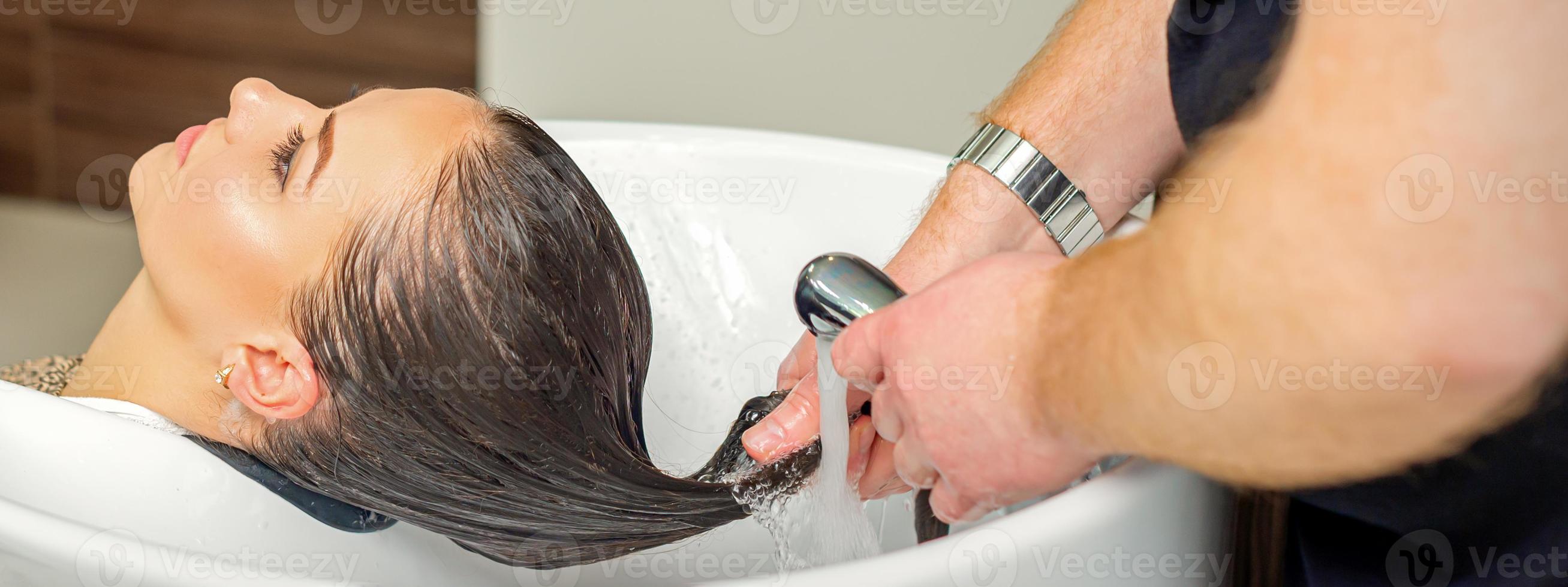 Hairdresser rinses hair of woman photo