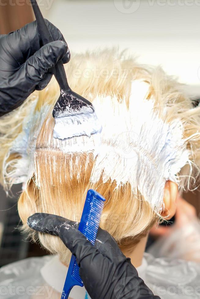 Hair stylist dyeing hair of woman photo