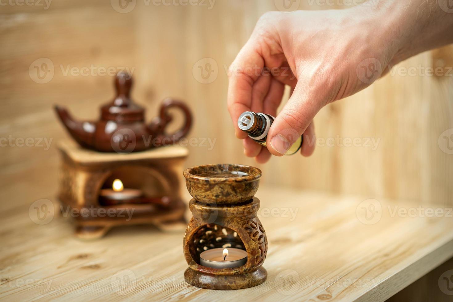 Hand pours essential oil to diffuser photo