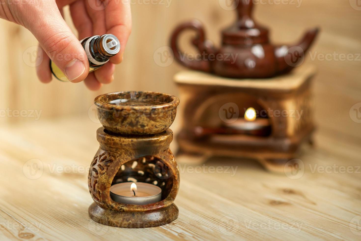 Hand pours essential oil to diffuser photo