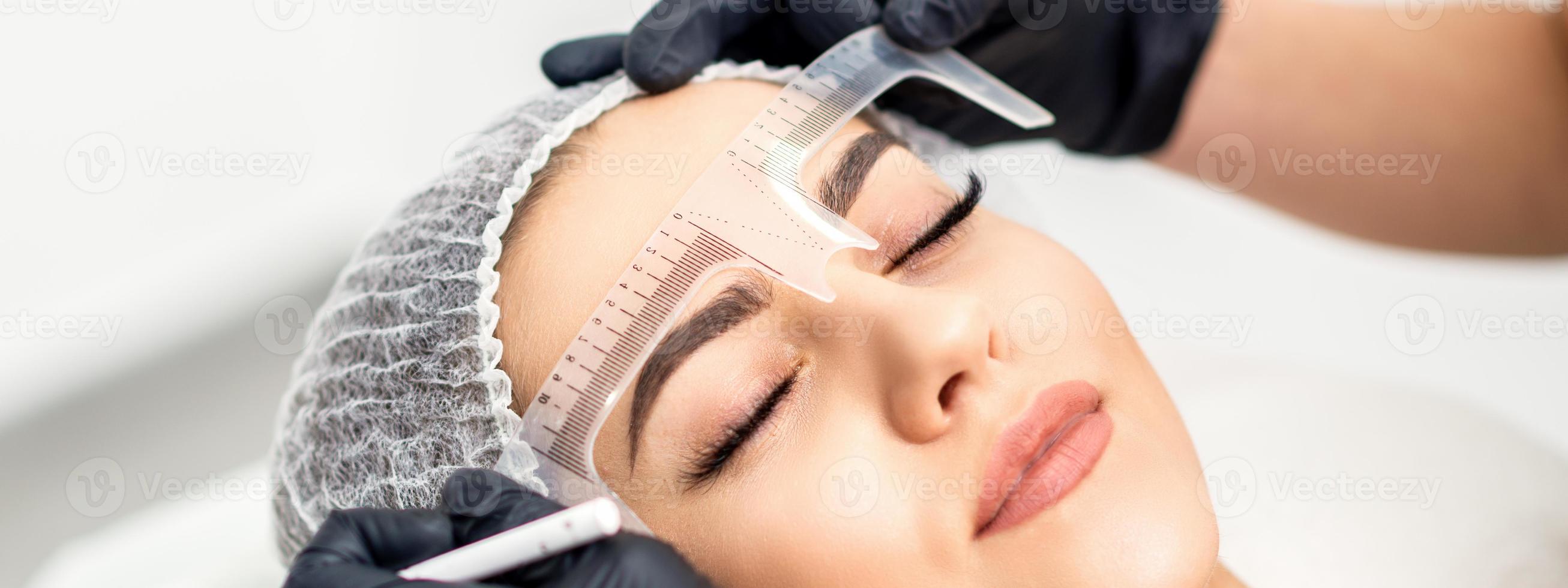 Beautician measuring brows with ruler photo