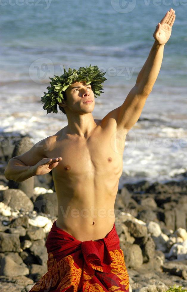 A hula dancer who is male is using his hands to gesture traditional Hawaiian symbols. photo