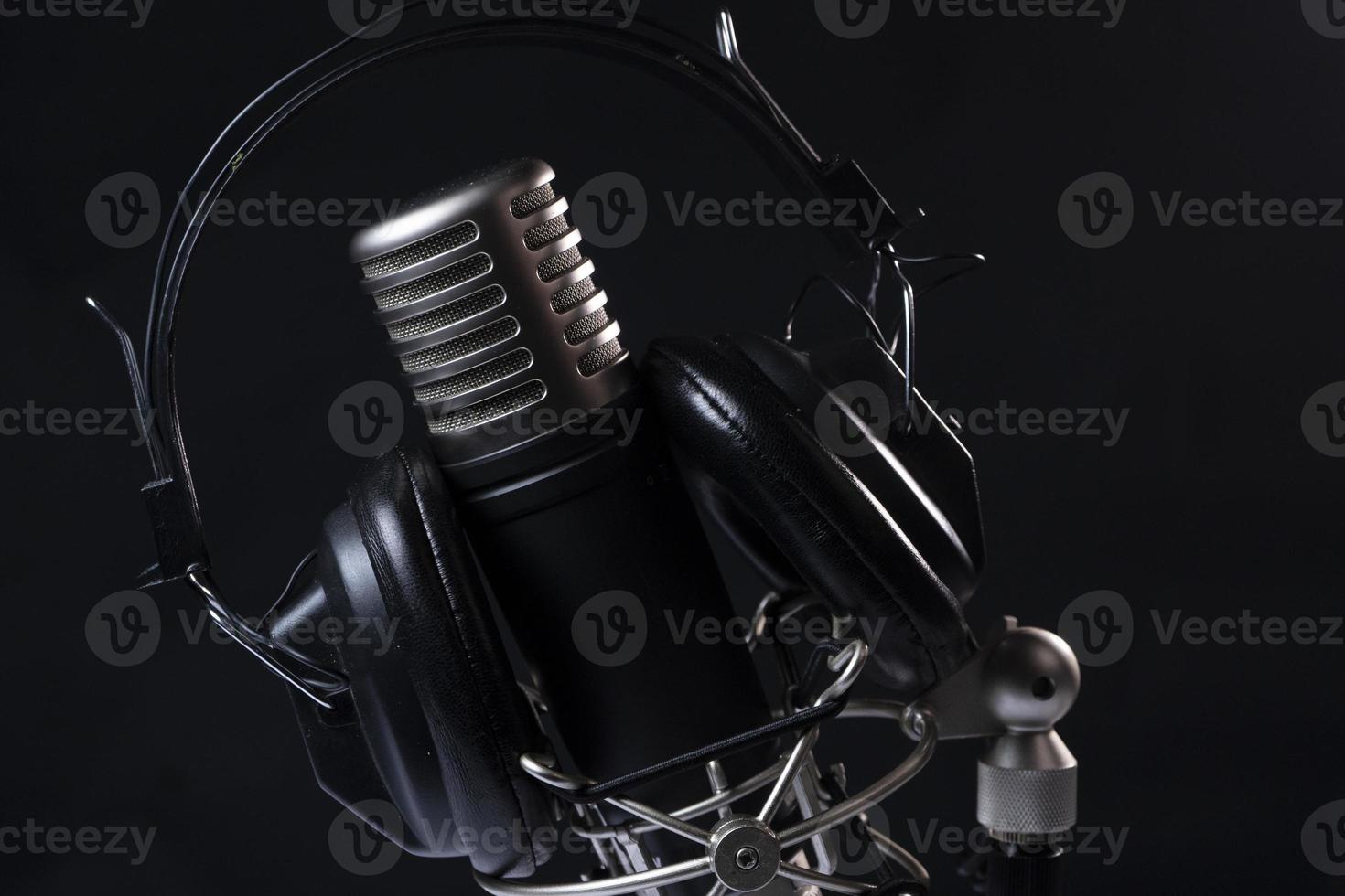 Professional microphone with black headphones over black background on white marble table photo