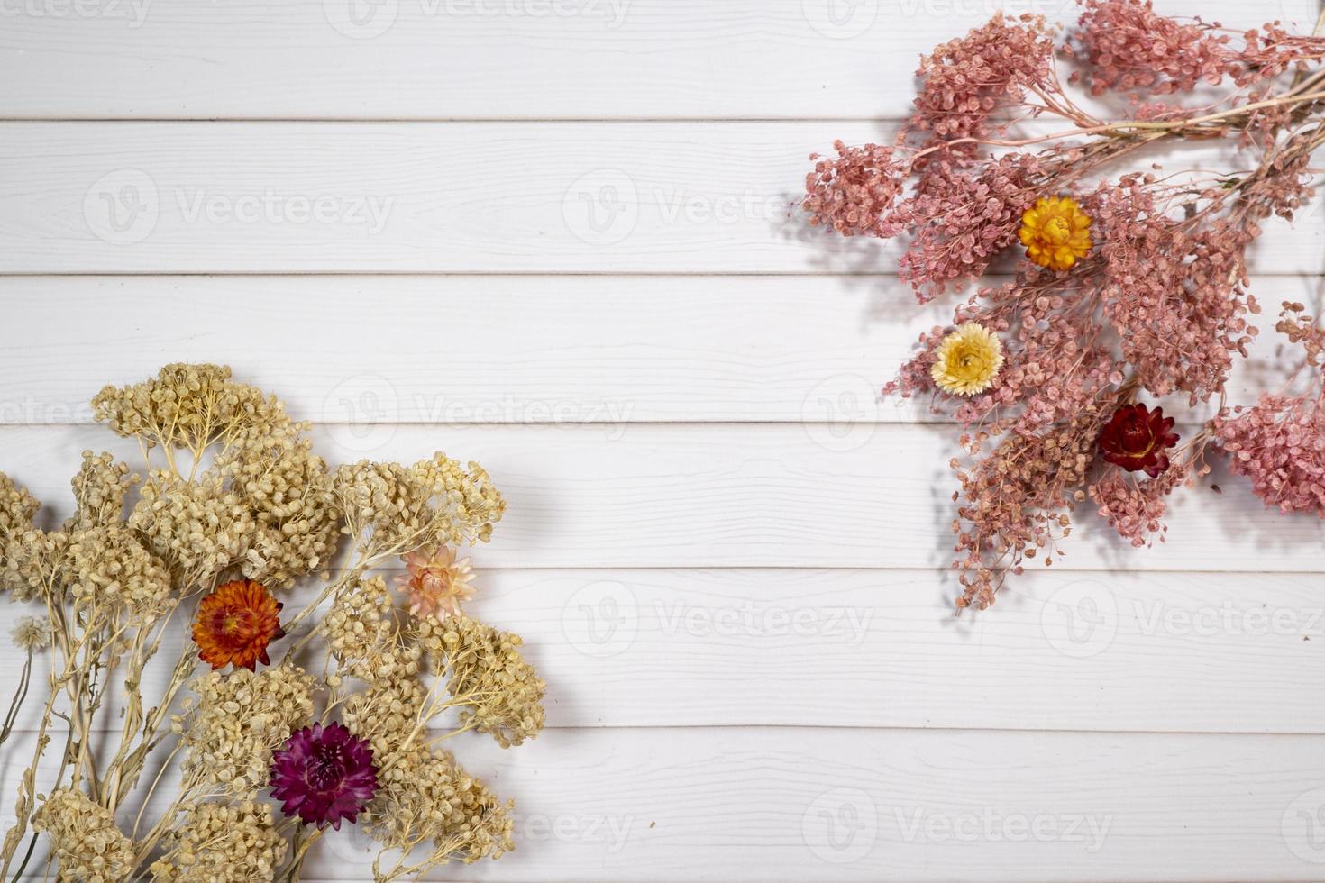 Top view of dry colorful flowers over a white wooden table with copy space photo