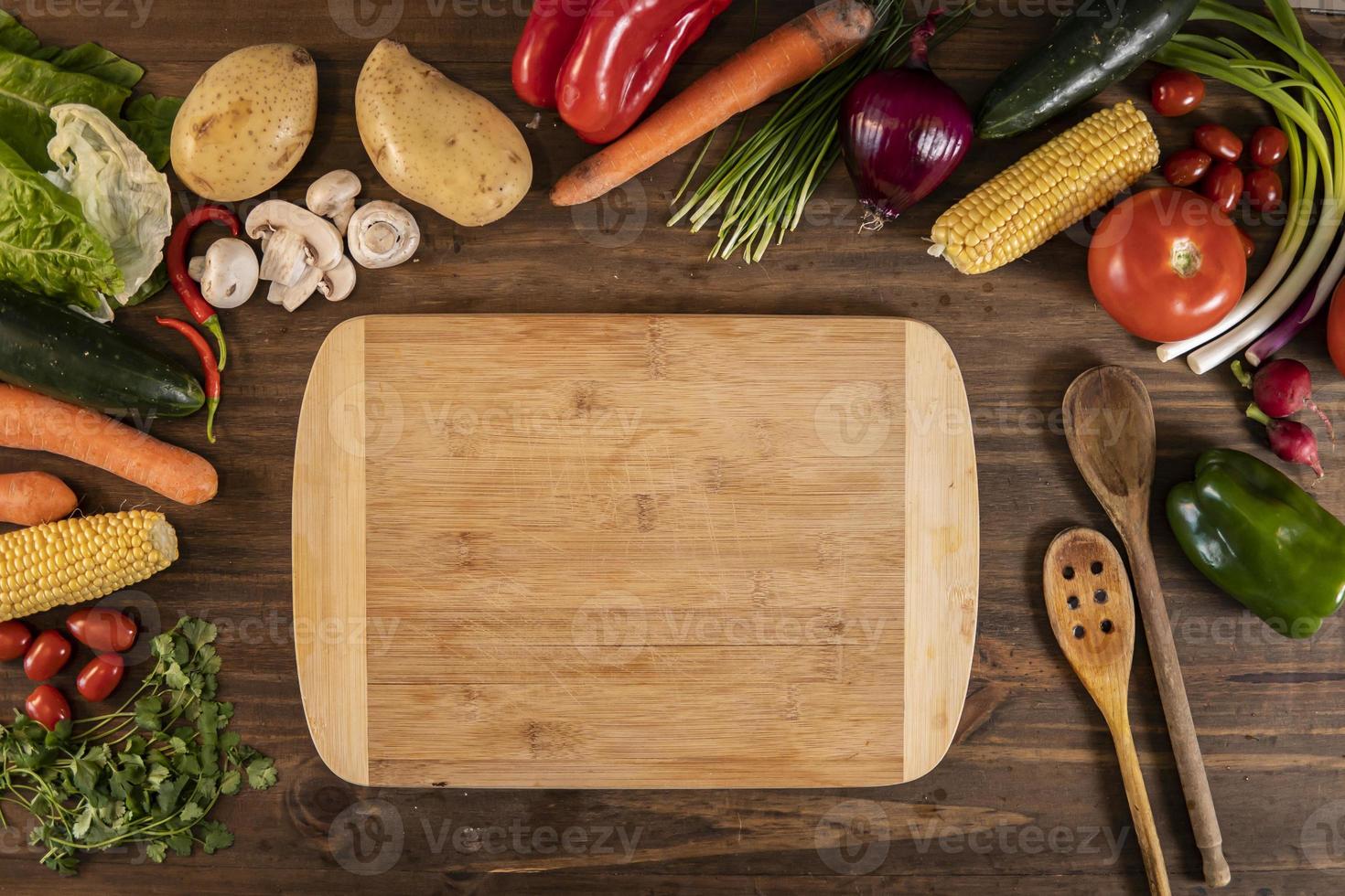 Flat lay of vegetables and food and a chopping table over a wooden table photo