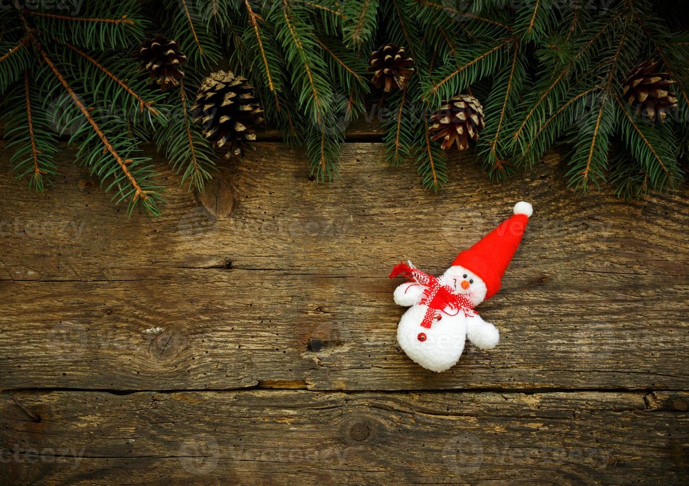 Christmas tree branches with snowman on wooden texture photo