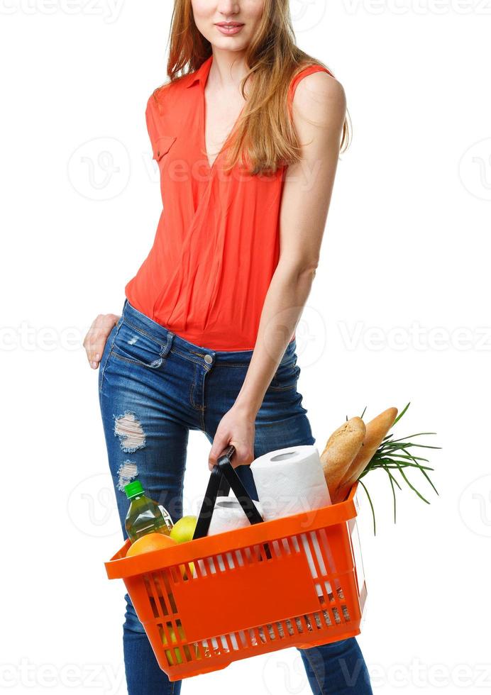 Happy young woman holding a basket full of healthy food on white. Shopping photo