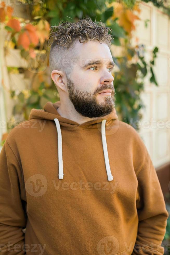 Close up shot of curly European male with beard wears switshot outdoors. Handsome man with crisp light hair. photo