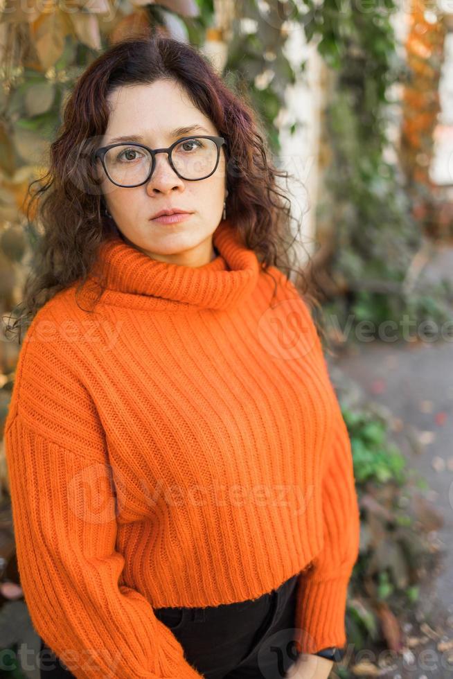 Portrait of carefree young woman smiling with urban background. Cheerful latin girl wearing eyeglasses in the city. photo