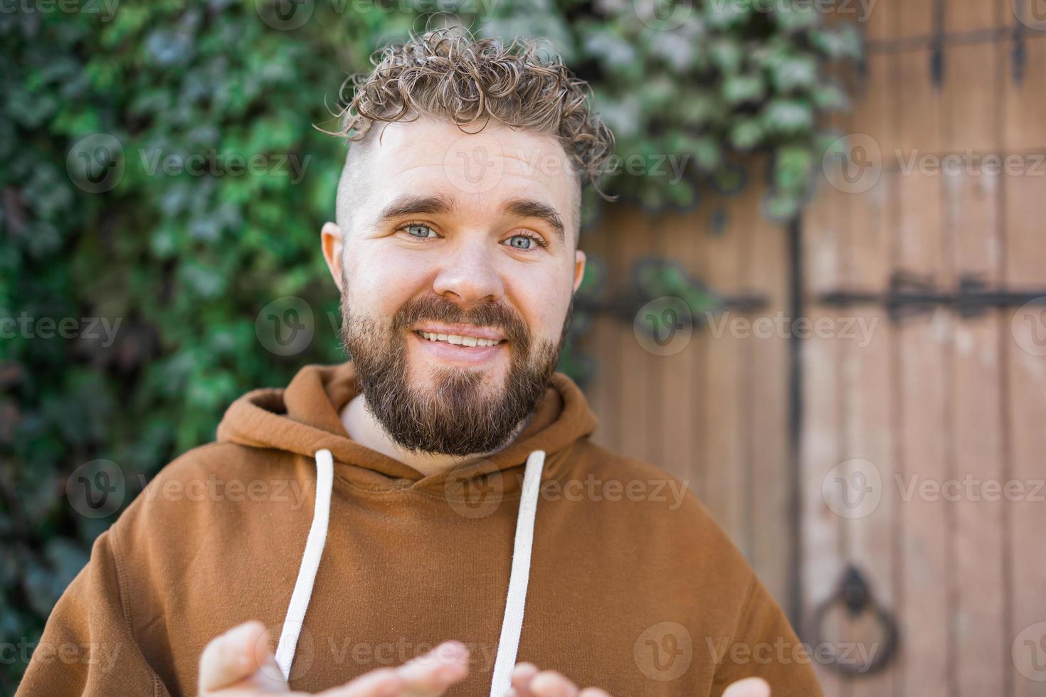 Handsome curly man takes a video of himself - video blog and youth blogger concept photo